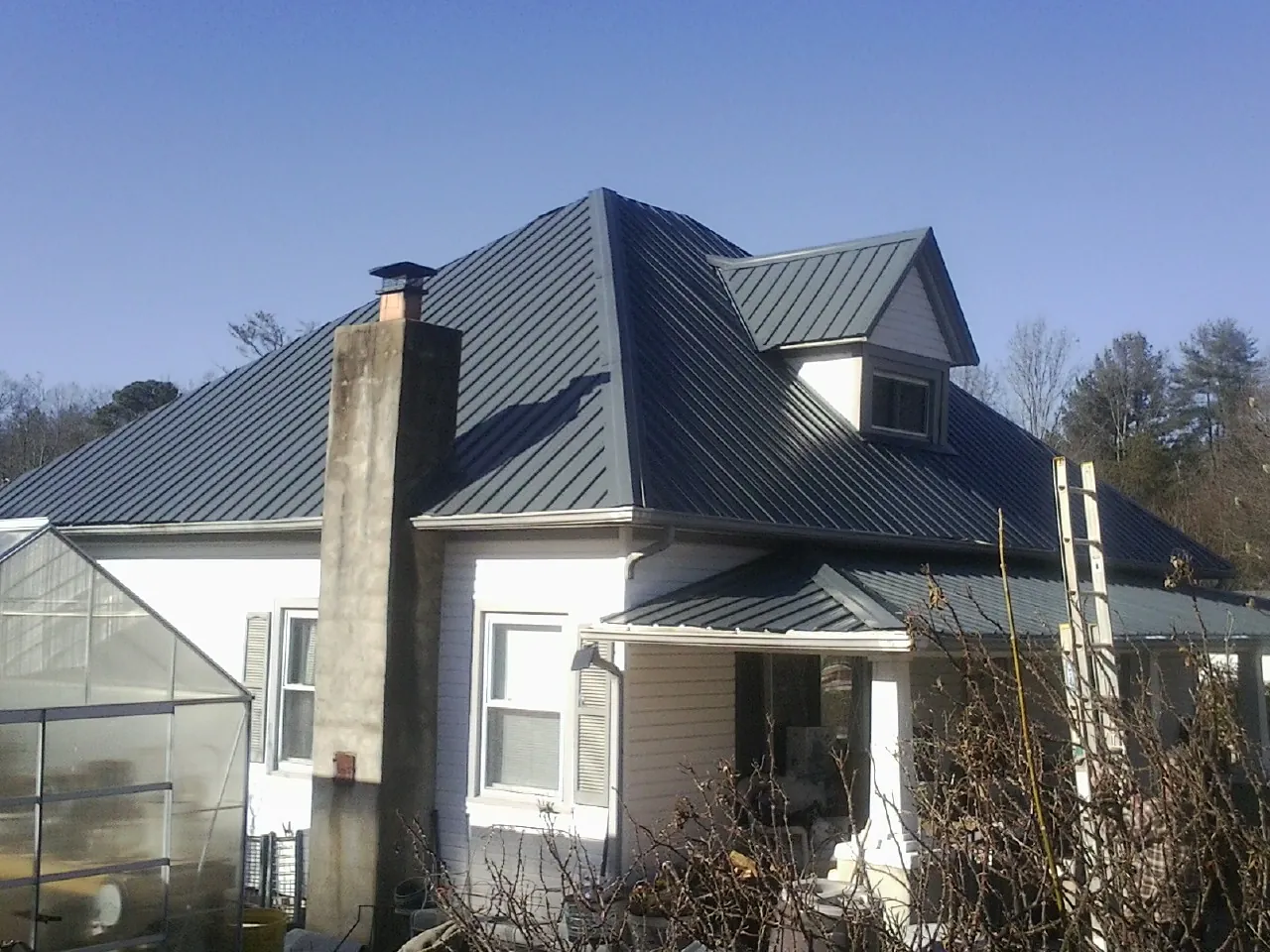 Dark blue standing seam metal roof on a white farmhouse with dormer — Slate & Tile Roof Repair by Roofing Brothers in Union Bridge
