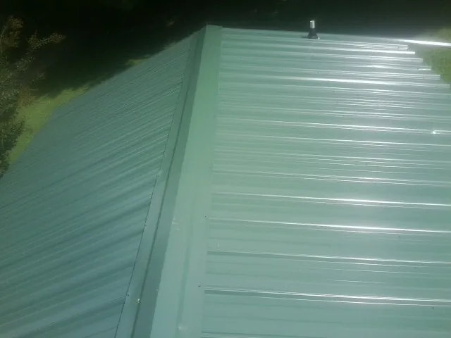 New green metal panels meeting at the ridge of a roof — Flat Roof Repair work by our crew in Union Bridge