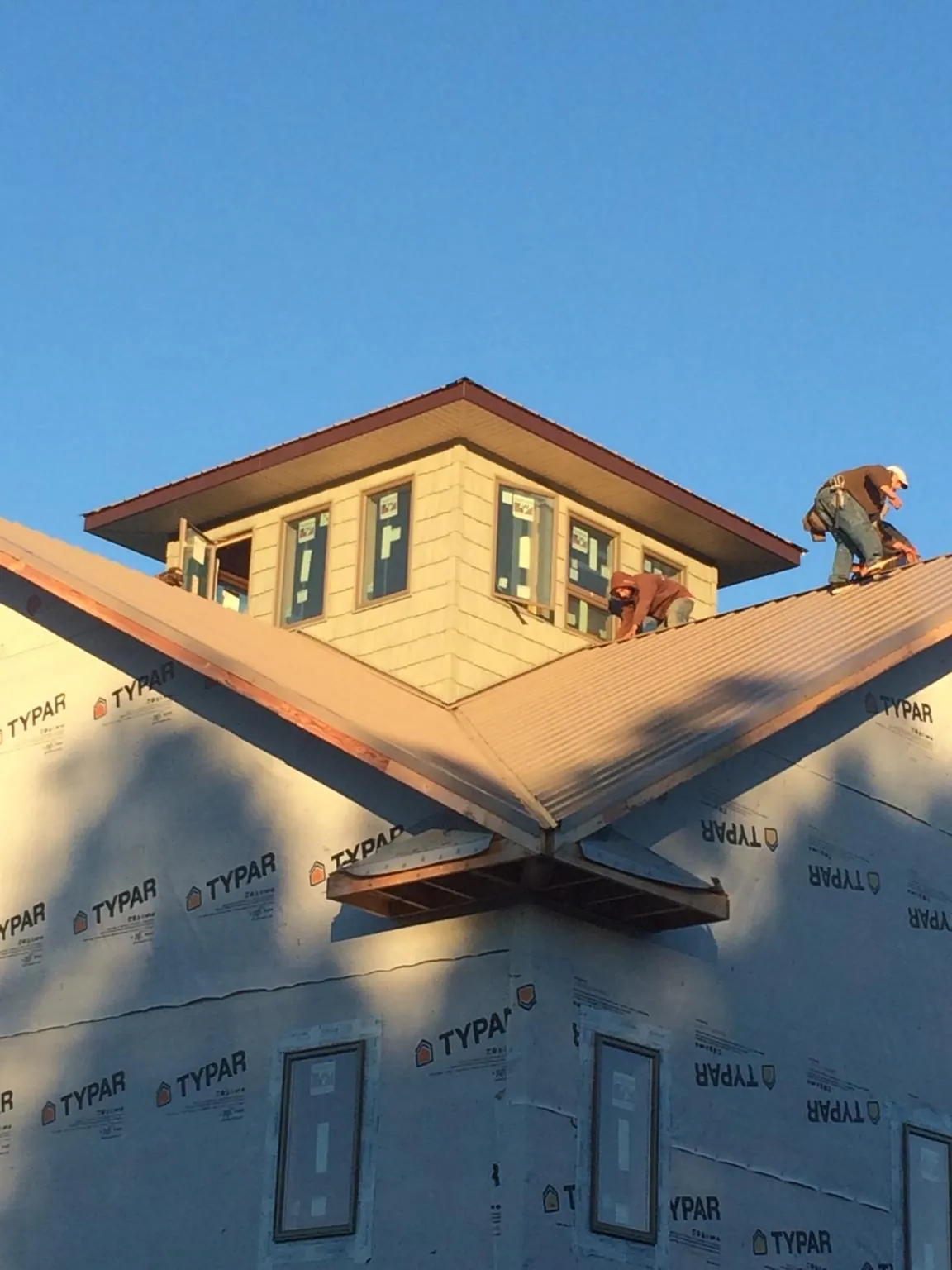 Roofers working around a rooftop cupola on a new metal roof at sunset — Roof Waterproofing in Union Bridge by Roofing Brothers
